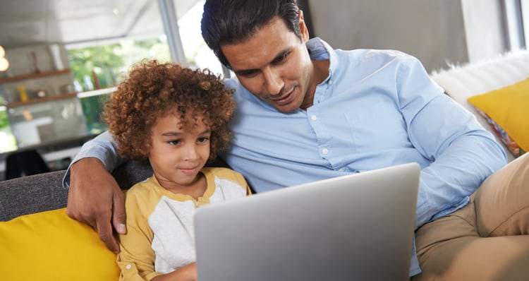 Photo of a parent and child looking at the screen of a laptop computer.
