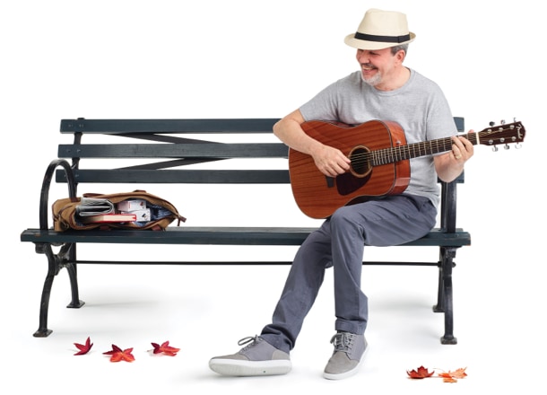 Image of Bob, who lives with hemophilia A with inhibitors, sitting on a bench holding a guitar. A bag is with NovoSeven&reg; RT products inside is open next to him.